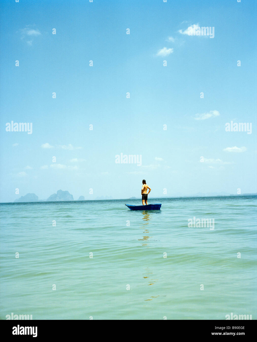 Un homme dans un petit bateau sur la mer bleue de la Thaïlande. Banque D'Images