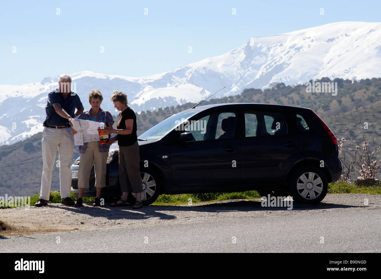 Les touristes avec leur voiture de location à la carte à avec un fond de montagne enneigées dans le sud de l'Espagne Sierra Tejeda Banque D'Images