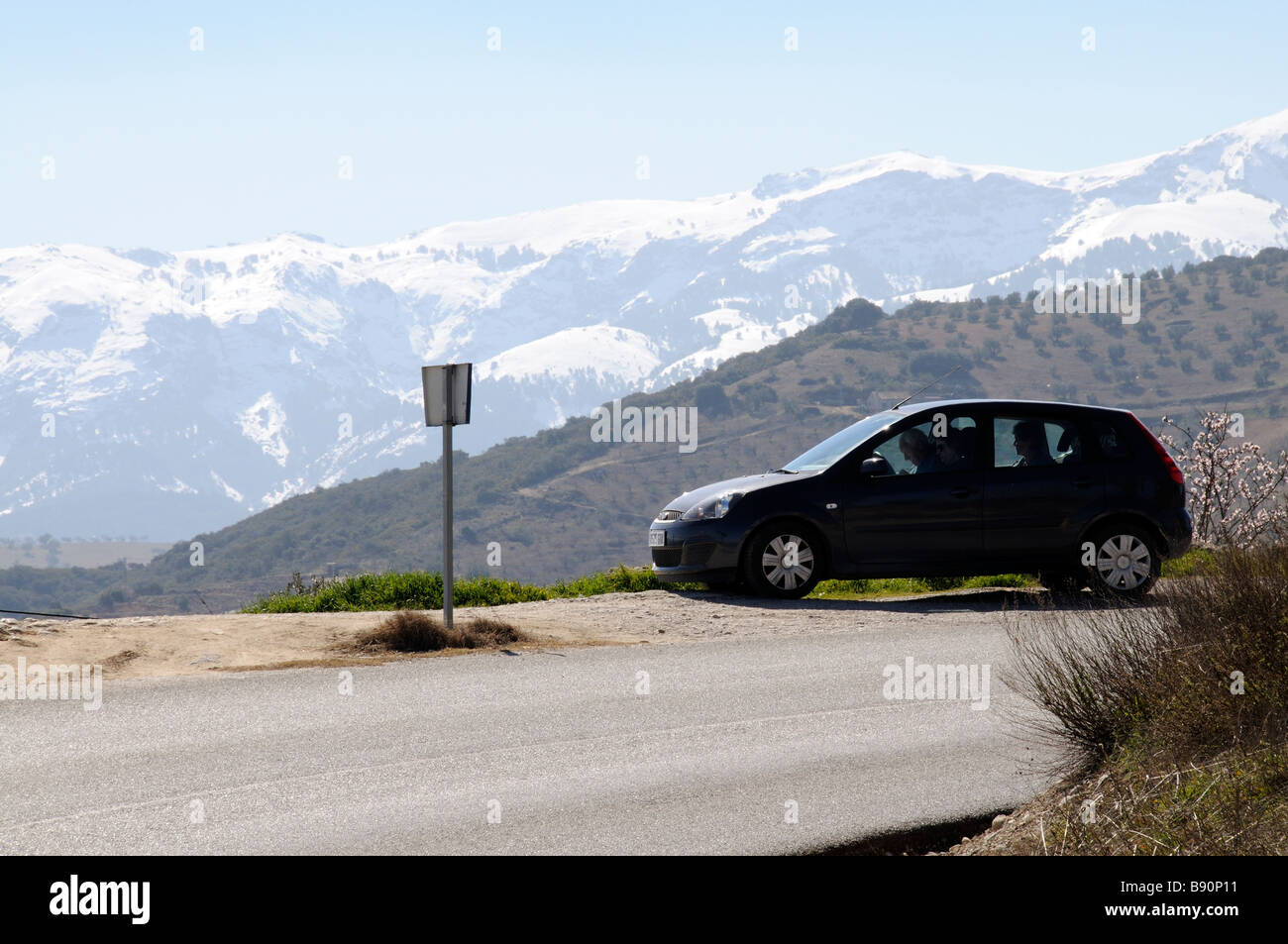 Les touristes assis dans leur voiture de location à la carte à avec un fond de montagne enneigées dans le sud de l'Espagne Sierra Tejeda Banque D'Images