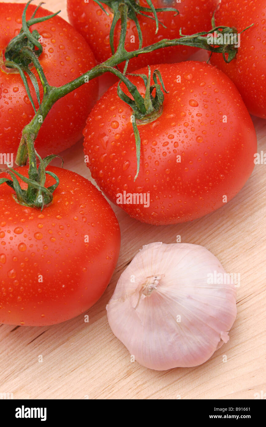 Les tomates et l'ail rouge rosée sur une planche à découper en bois Banque D'Images