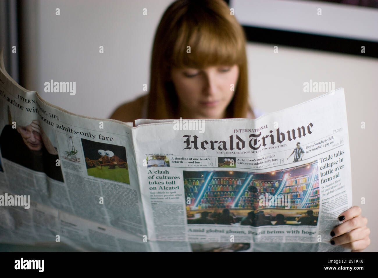Jeune femme lisant un journal quotidien le Herald Tribune usa journal américain Banque D'Images