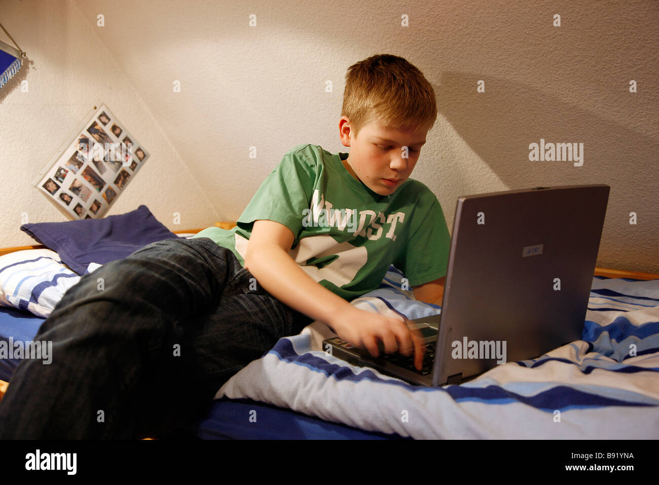 Un garçon, 13 ans, travaille à son ordinateur portable posé sur son lit  dans sa chambre de l'enfant Photo Stock - Alamy