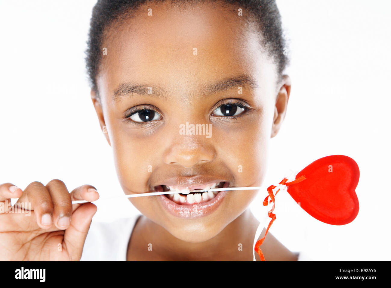 Young Girl holding heart lollipop dans ses dents Banque D'Images