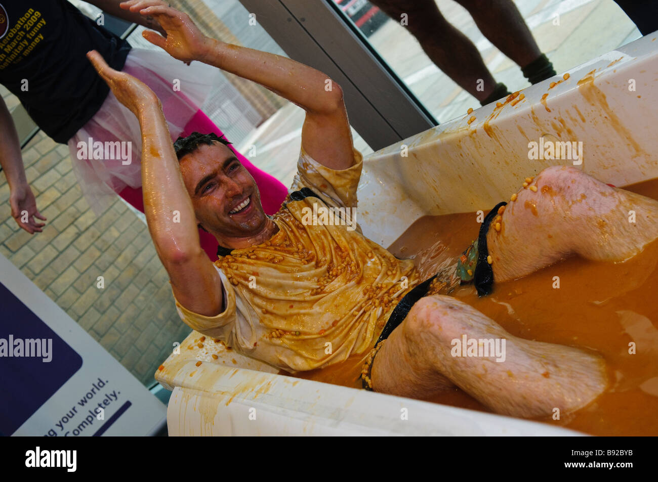 L'homme dans une baignoire pleine de haricots cuits au four Banque D'Images