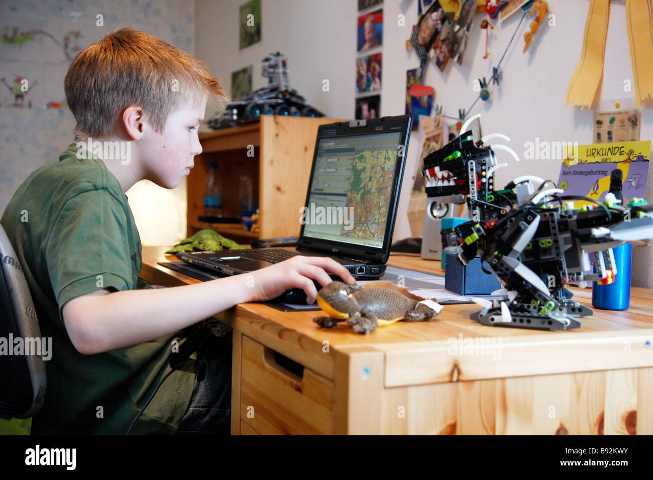 Un garçon, 11 ans, travaille à un ordinateur portable dans sa chambre de l'enfant. Il est en train de faire leurs devoirs de géographie et travaille avec un logiciel de carte. Banque D'Images