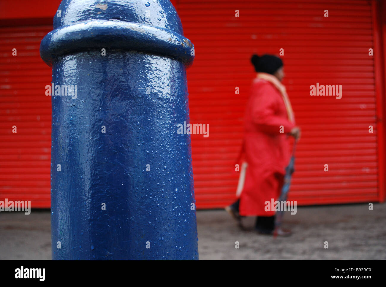 Femme en rouge passant marché de Brixton Banque D'Images