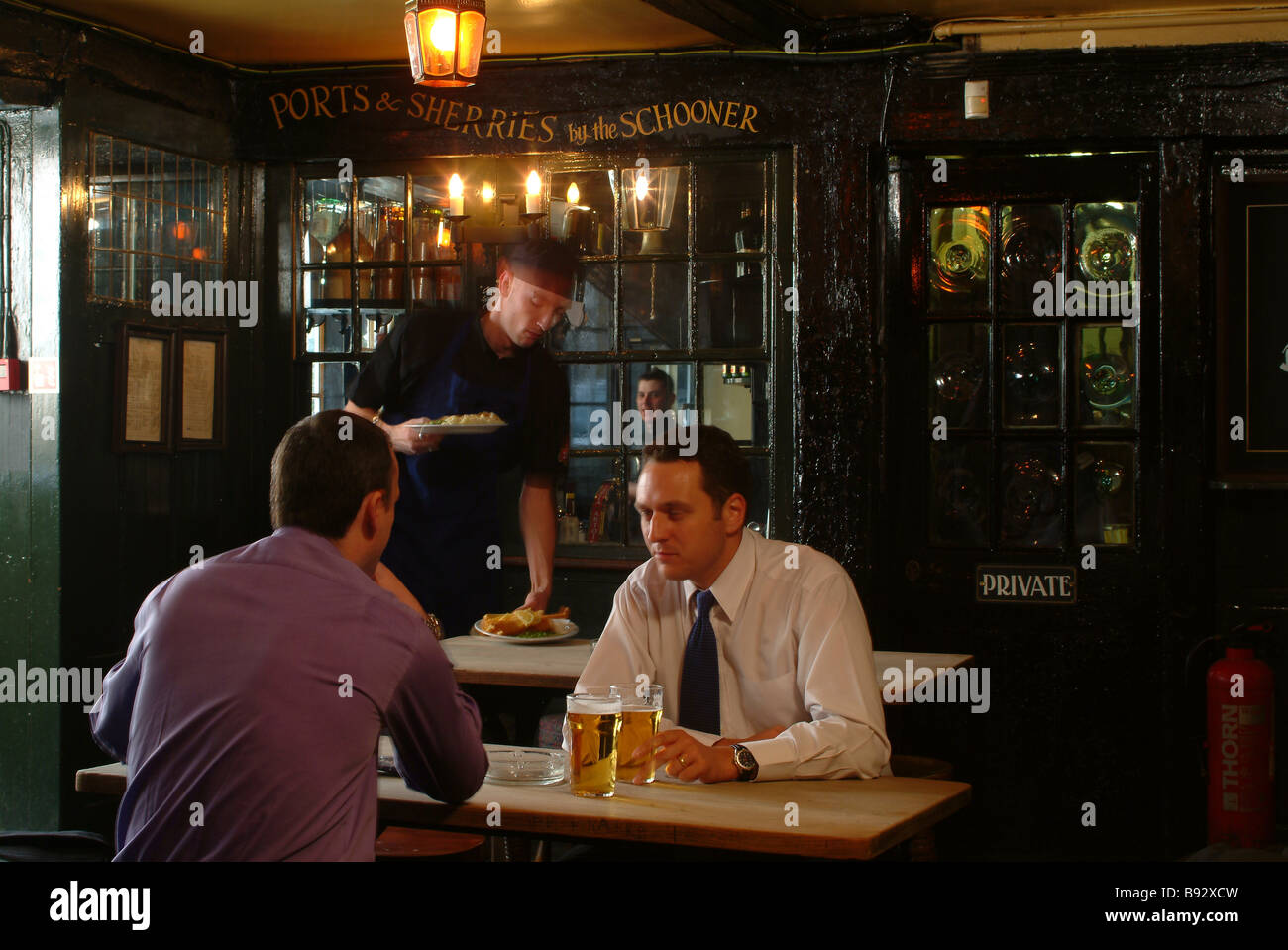 Deux hommes assis dans un bar ayant une pinte de bière blonde Banque D'Images