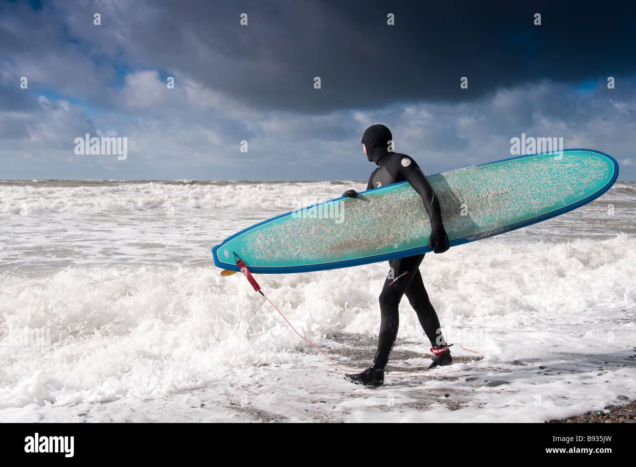 Un internaute portant bikini surf board en voyant la mer agitée Aberystwyth Wales UK Banque D'Images
