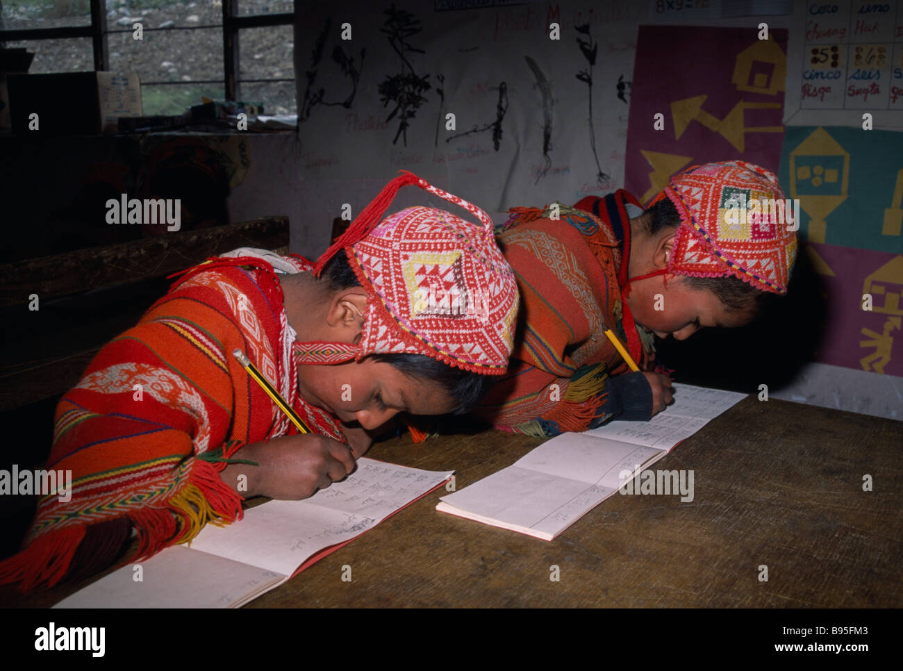 Andes Pérou Cusco Tastayoc Village. Les Indiens Quechua enfants portant des vêtements traditionnels à l'école écrit au bureau. Banque D'Images