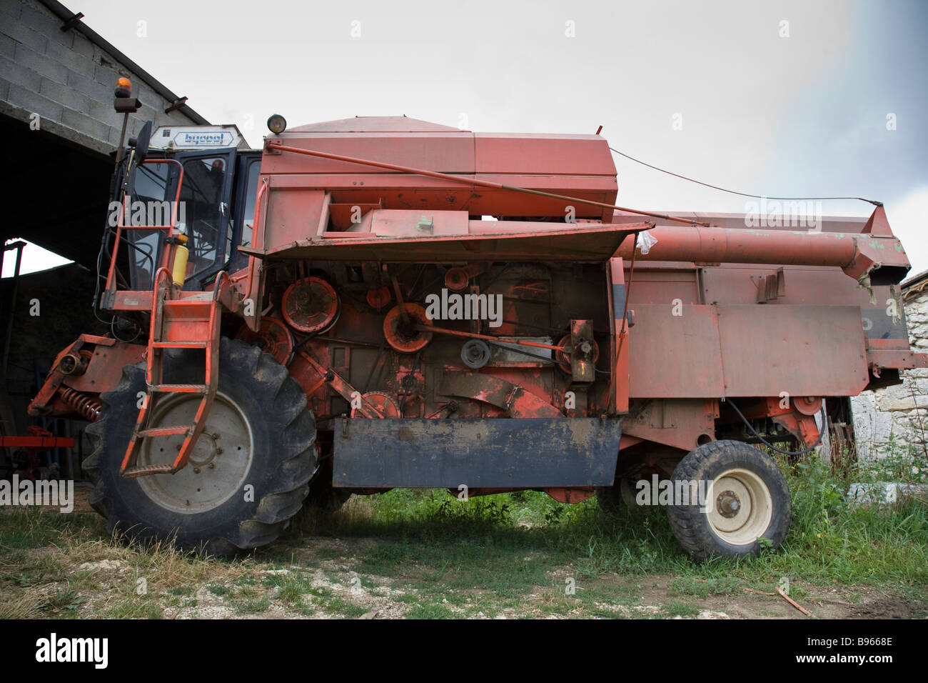 Une vieille moissonneuse batteuse garée dans une ferme en France. Banque D'Images