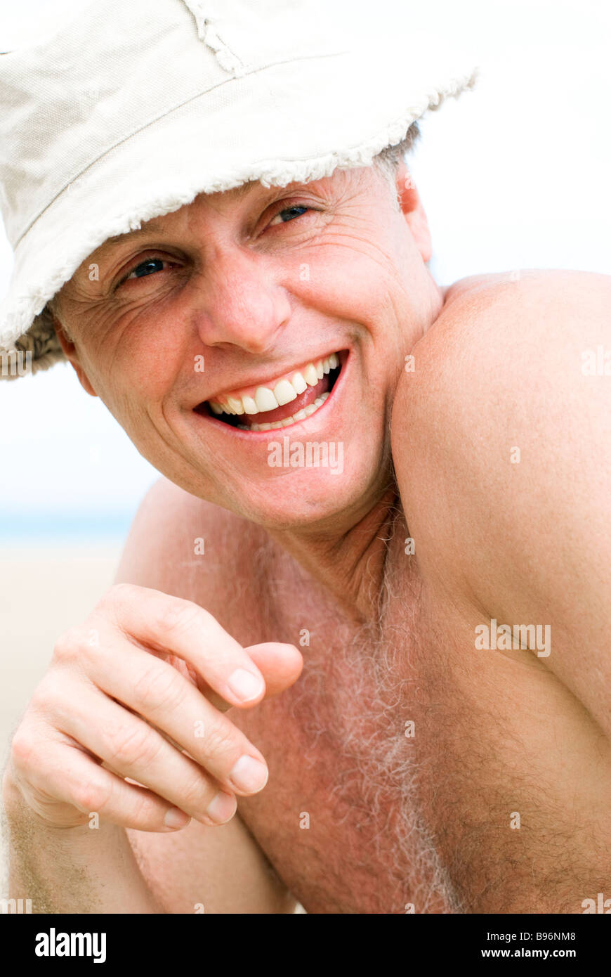Le portrait d'une quarantaine de rire heureux homme portant un chapeau de plage sur une journée ensoleillée. Banque D'Images
