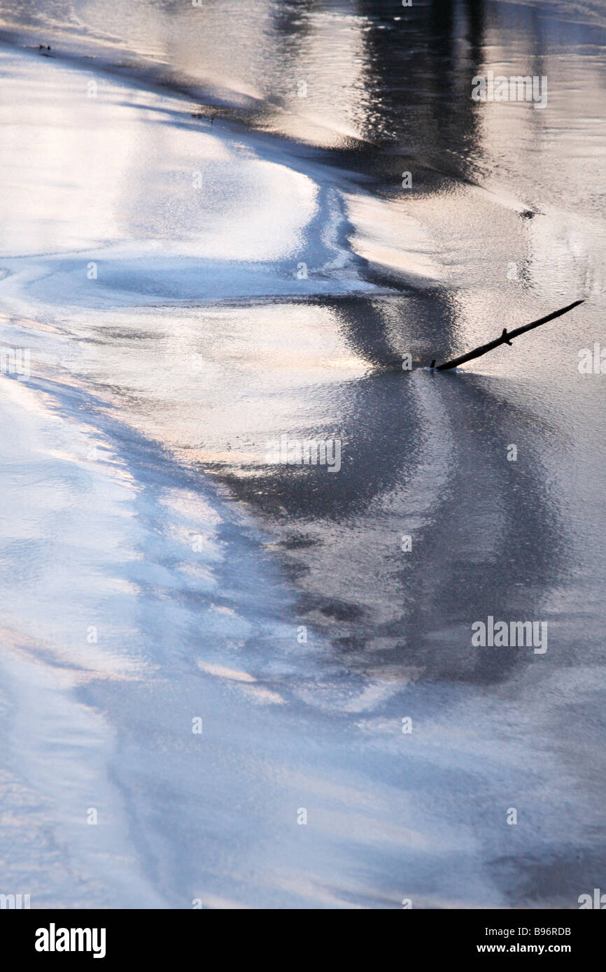 Abstract. La glace de rivière reflétant les arbres et ciel au crépuscule. Banque D'Images