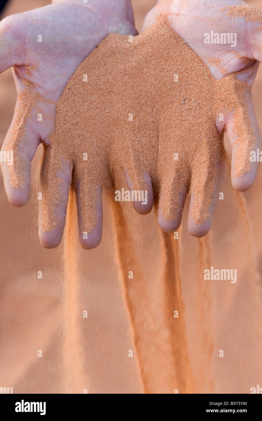Le sable du Kalahari rouge passe par les doigts d'une main les personnes Banque D'Images