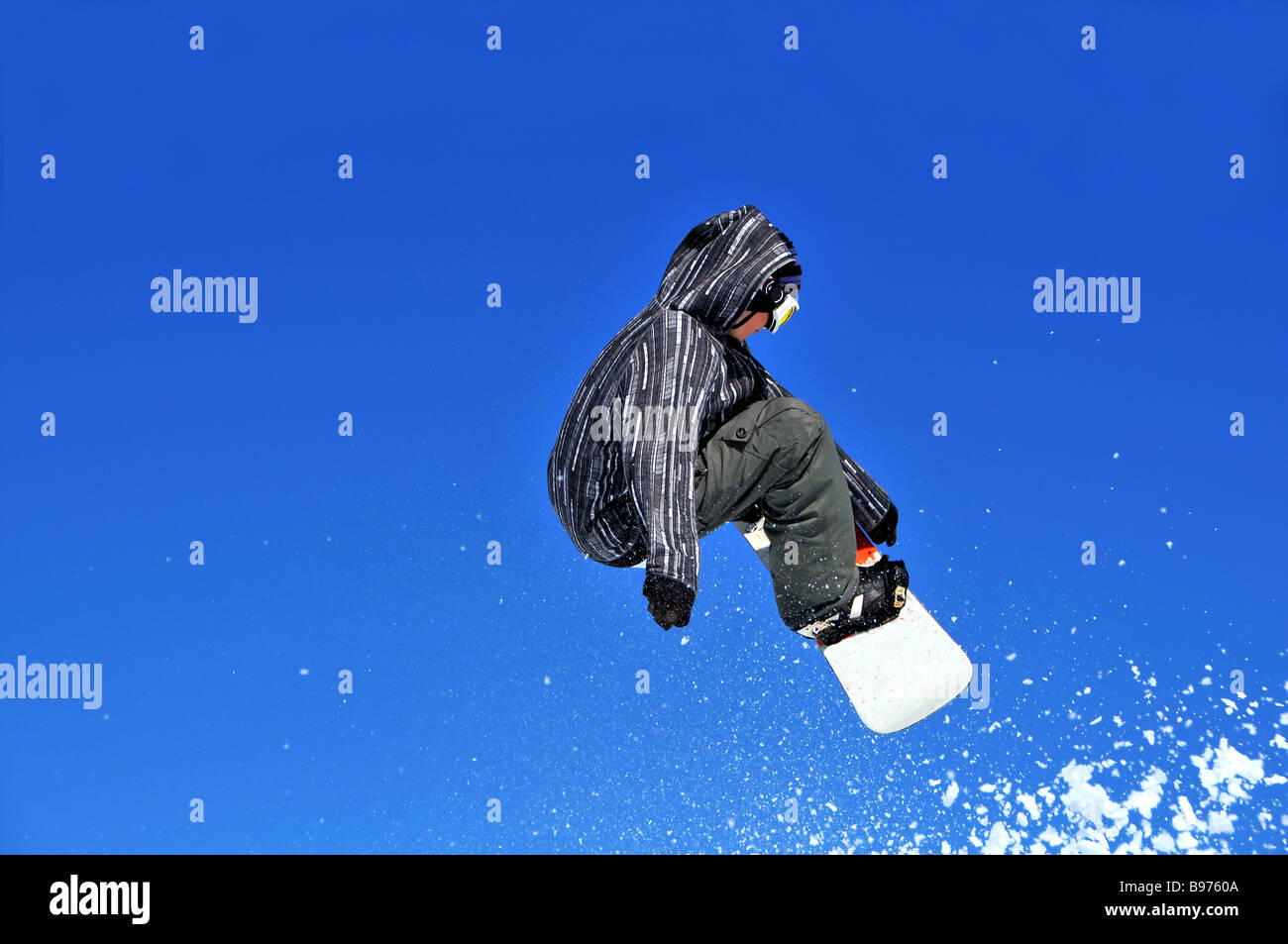 Une fille planchiste effectuer un saut et suivie par beaucoup de neige Banque D'Images