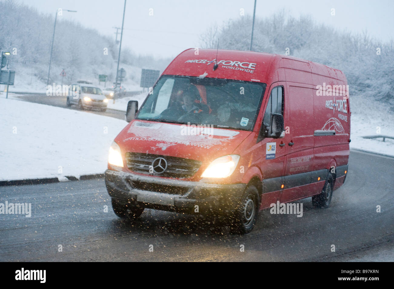 Red royal mail Parcel Force van roulant le long d'une route couverte de neige sur une journée l'hiver en Angleterre Banque D'Images
