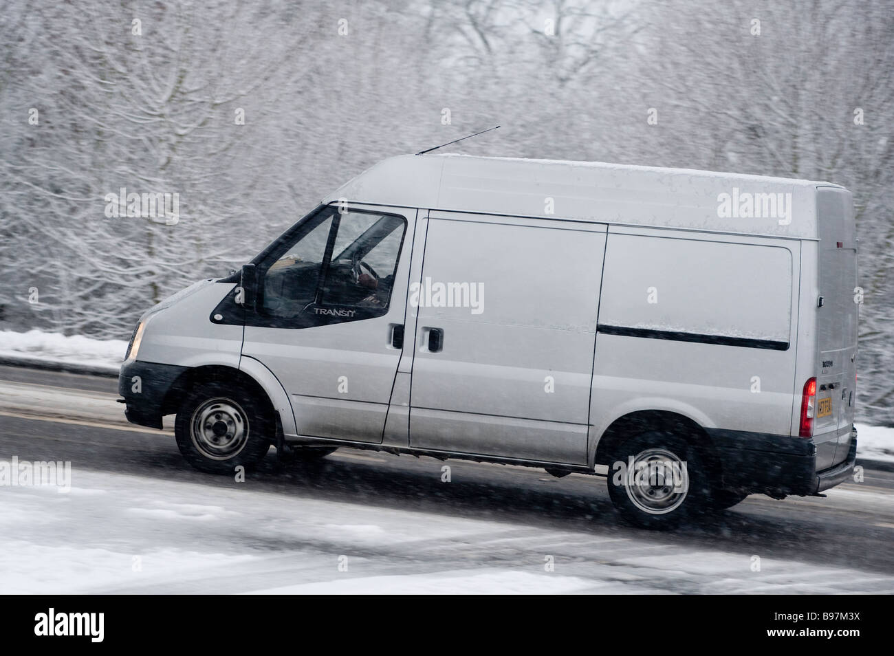 Vue latérale d'une fourgonnette roulant le long d'une route enneigée lors d'une journée hivernale en Angleterre. Banque D'Images
