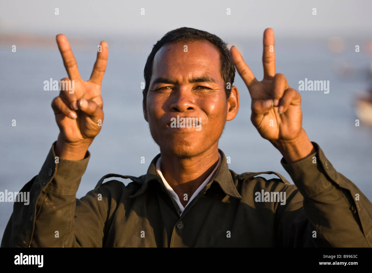 Man holding up mains avec le signe de la paix Phnom Penh Cambodge Riverside Banque D'Images