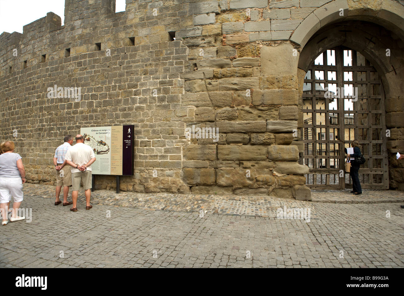 Les touristes d'examiner une carte touristique à l'extérieur des murs du château à Carcassonne Languedoc France Banque D'Images