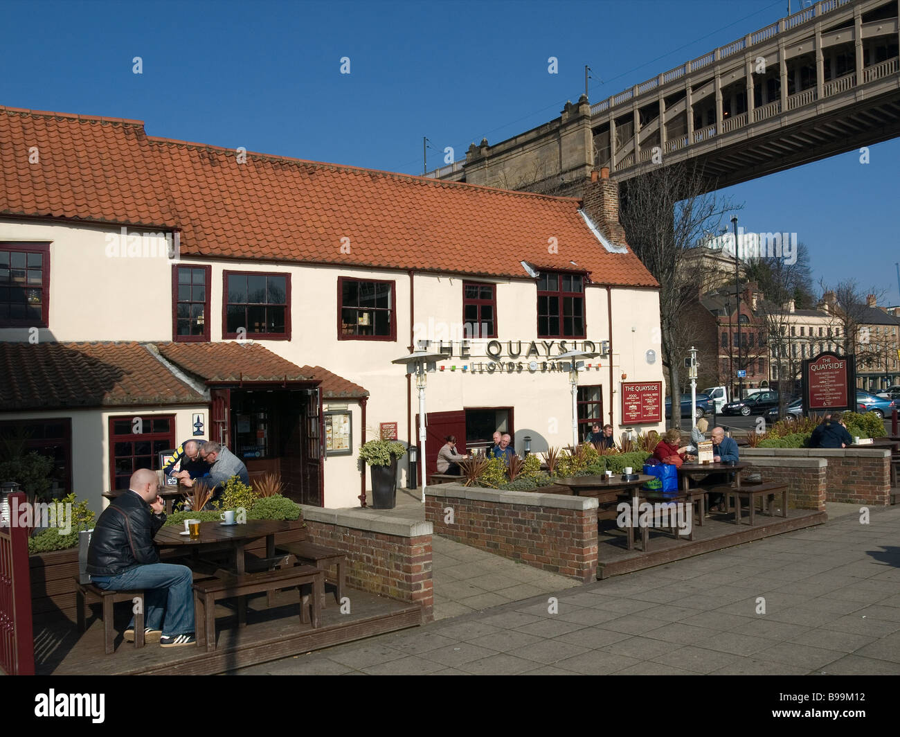 Bar Lloyds sur la rive de la rivière Tyne Newcastle avec le haut niveau historique route rail bridge derrière Banque D'Images