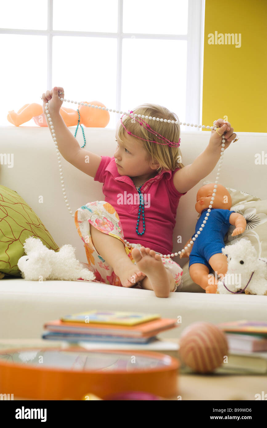 Petite fille assise sur le canapé avec des jouets, jouer avec les Bijoux de  costume Photo Stock - Alamy