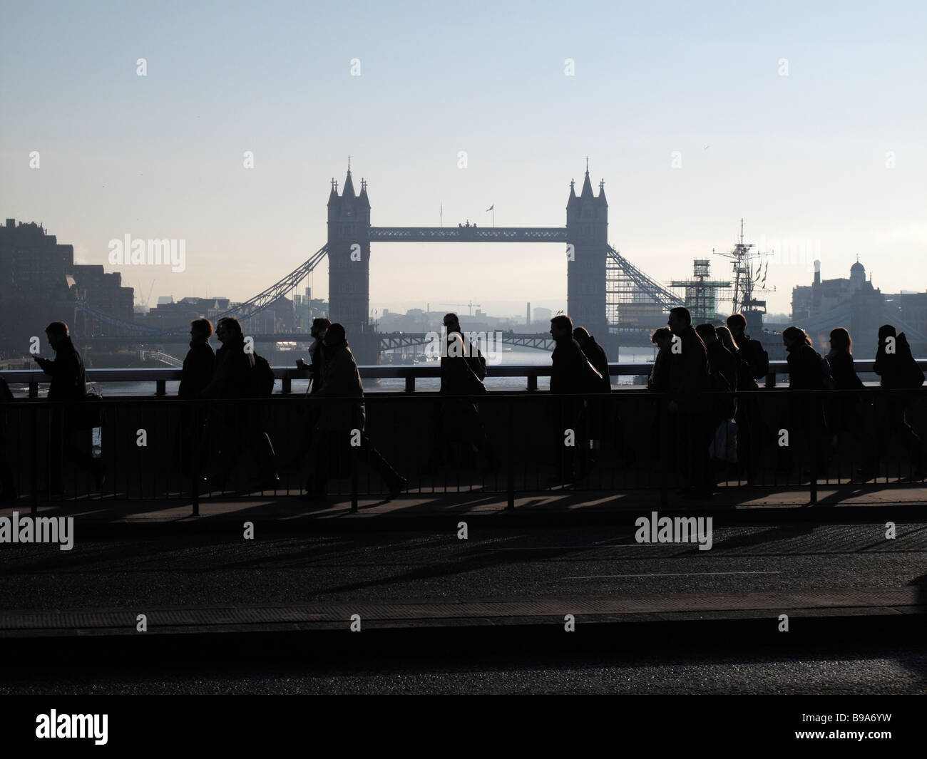 Silhouettes de banlieusards se dépêchant de travailler à travers le pont de Londres avec le Tower Bridge en arrière-plan Banque D'Images