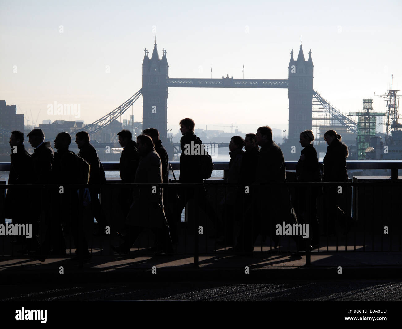 Silhouettes de banlieusards se dépêchant de travailler à travers le pont de Londres avec le Tower Bridge en arrière-plan Banque D'Images