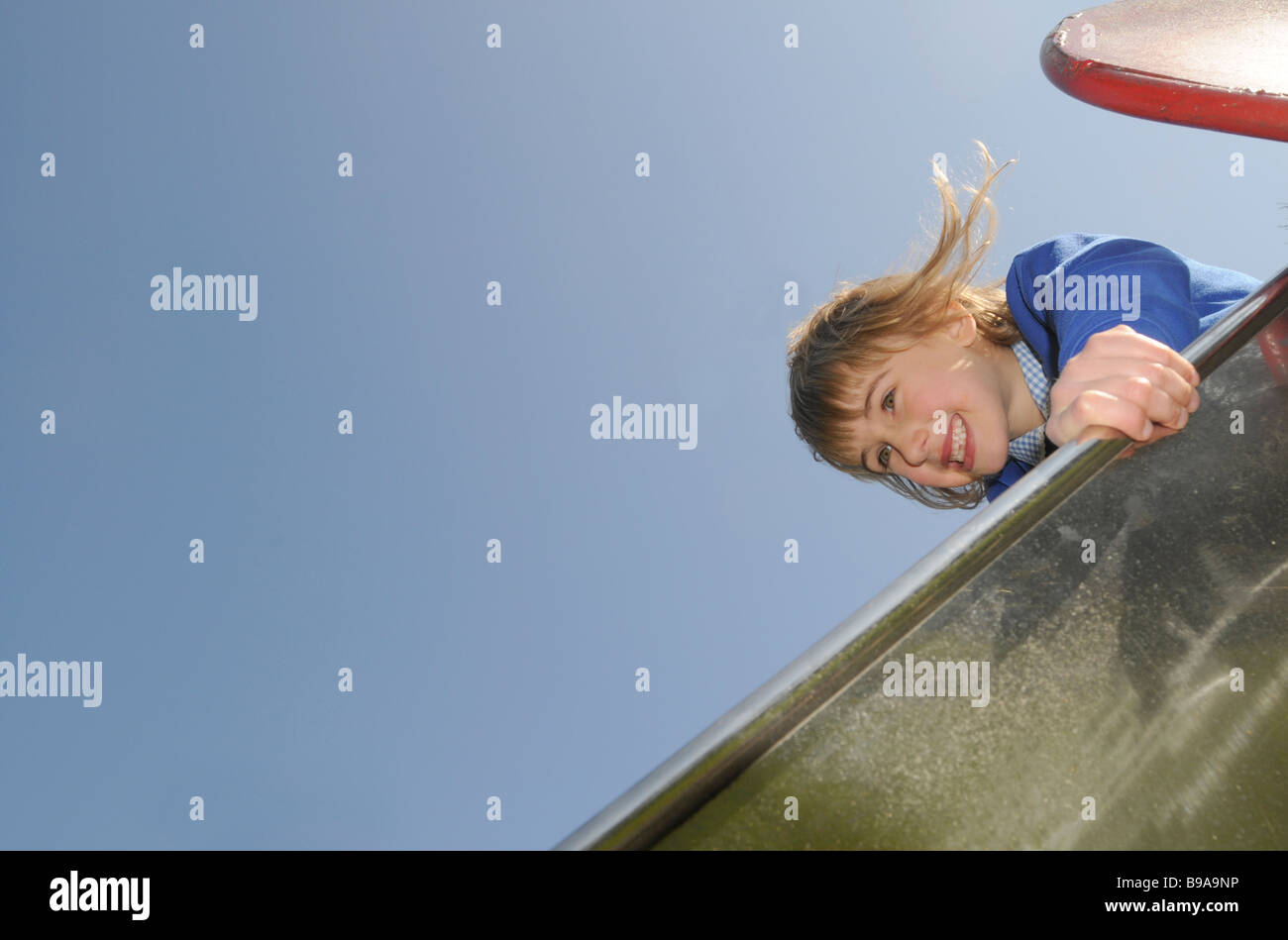 Une fillette de six ans dans son école uniforme sur une aire de glisse Banque D'Images