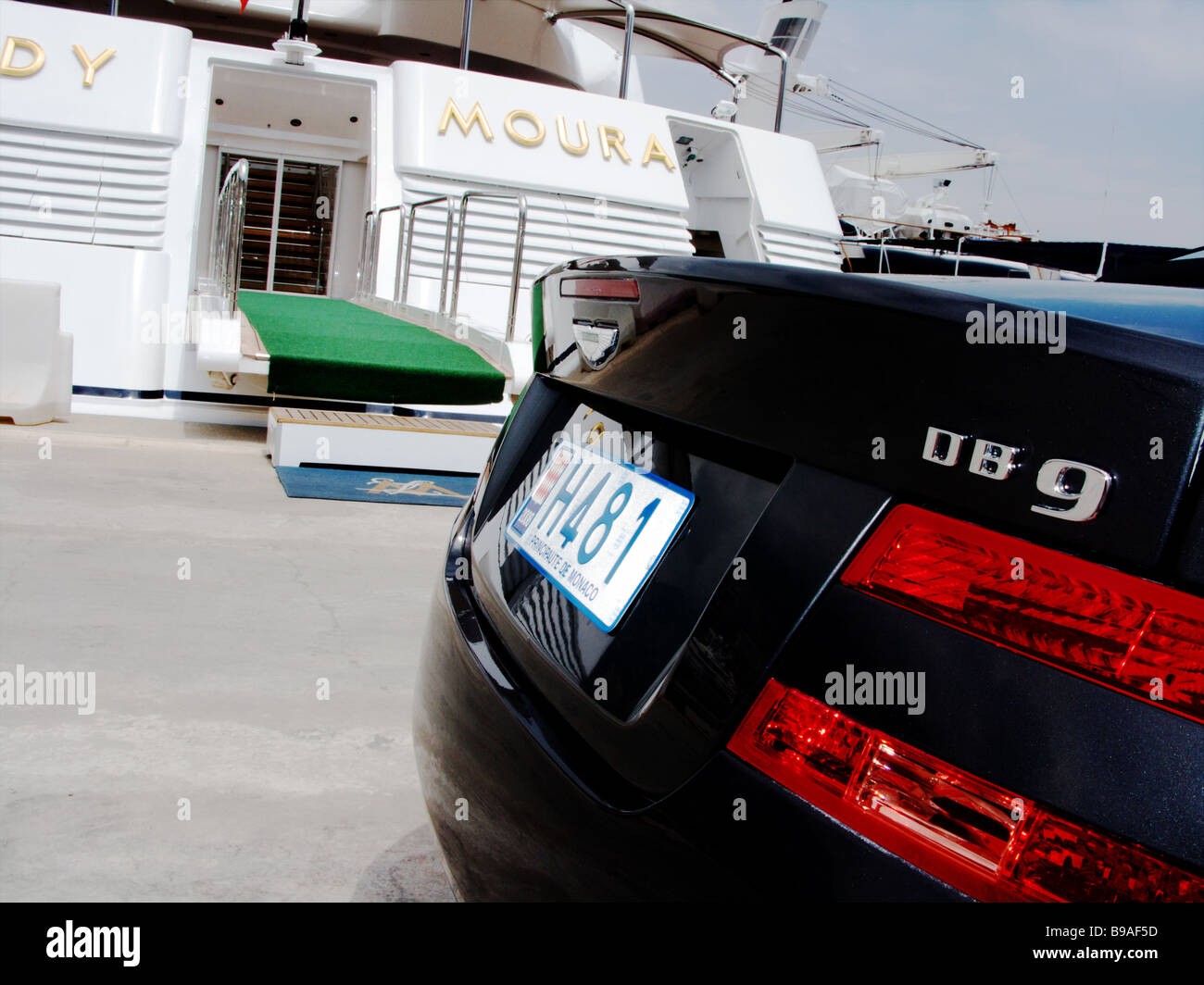 Une Aston Martin DB9 bleue garée à côté de la Dame Moura super yacht de luxe amarrés dans le port de Monaco Monte Carlo. Banque D'Images