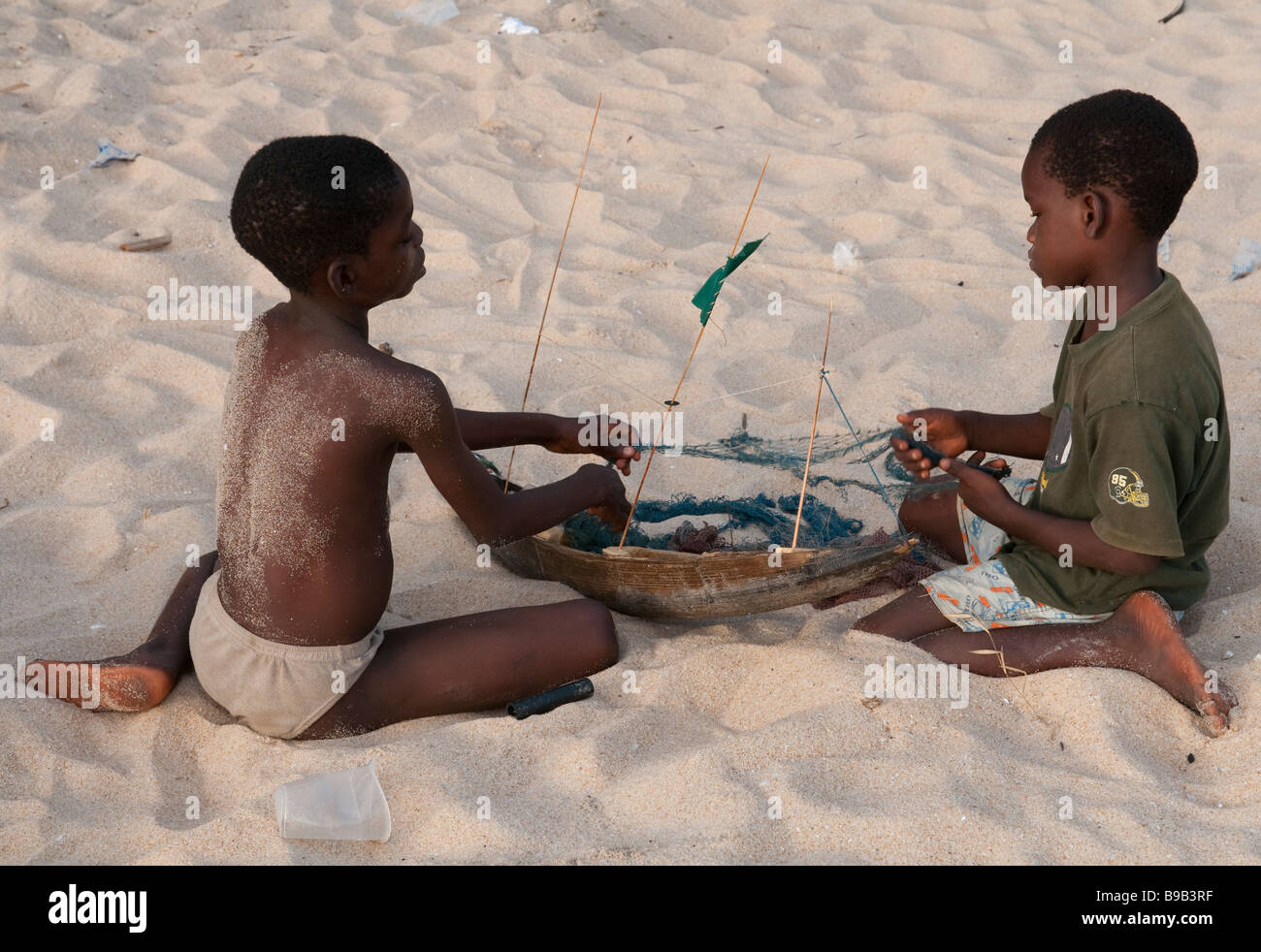 L'Afrique de l'ouest de Cape Coast au Ghana 2 garçons la construction d'un modèle de bateau de pêche sur la plage Banque D'Images