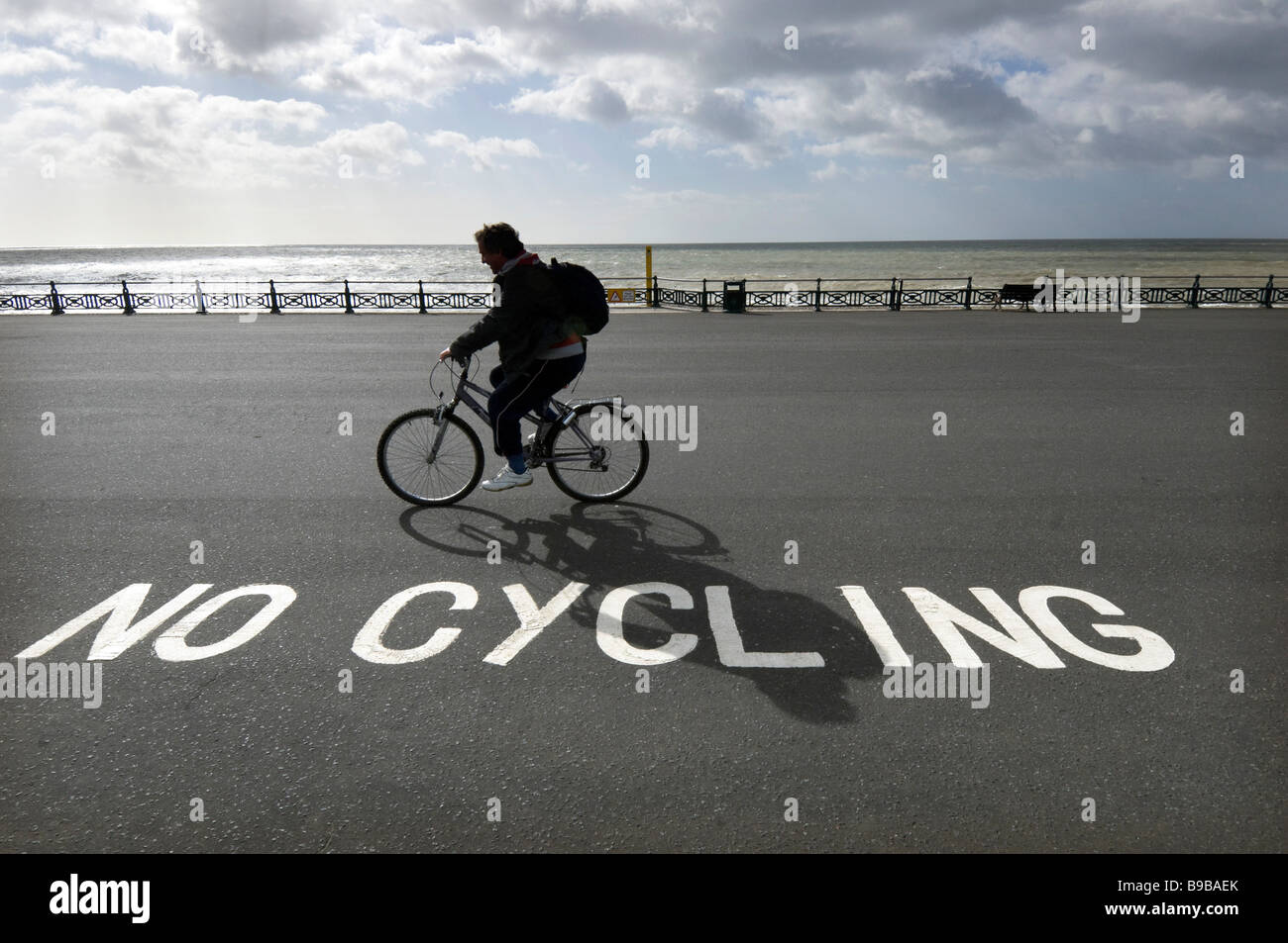 Un cycliste ignorer un 'Pas de vélo signe sur le front de mer de Brighton et Hove. Banque D'Images