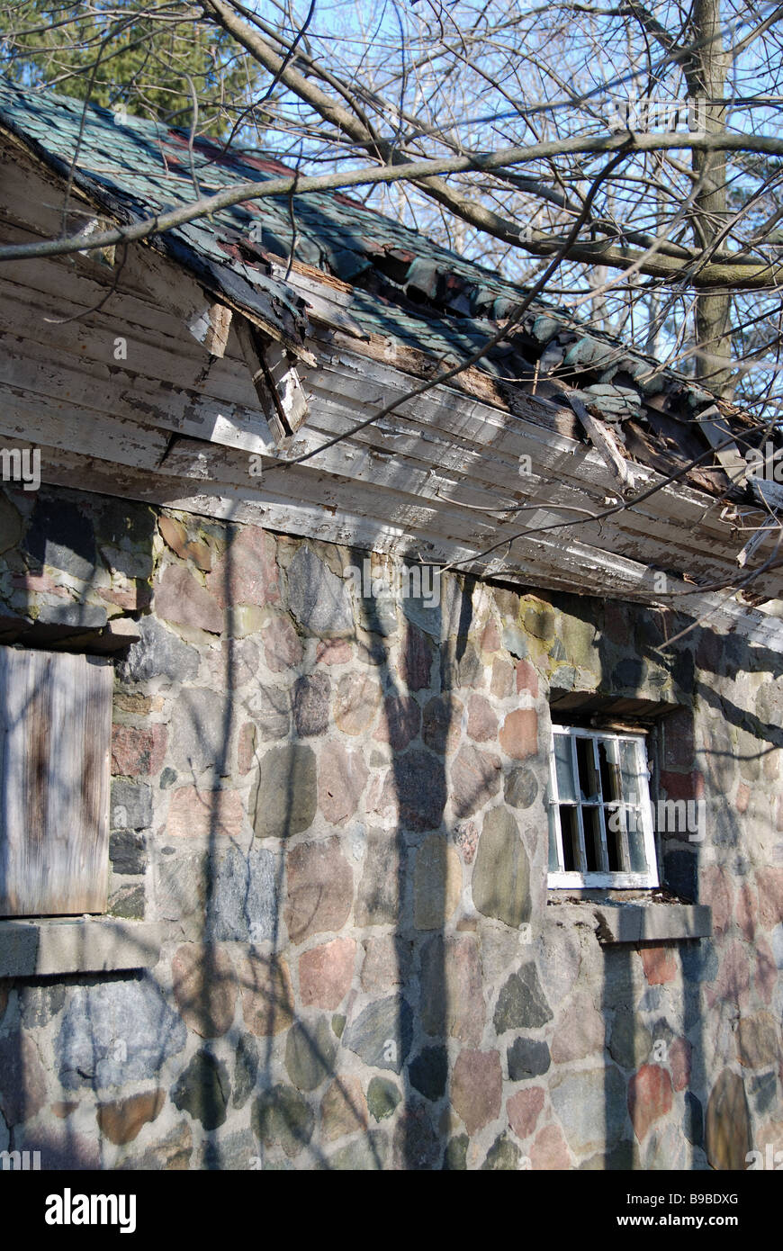 Une vieille maison en pierre avec brisé des fenêtres et un toit en décomposition dans le besoin de réparation. Banque D'Images