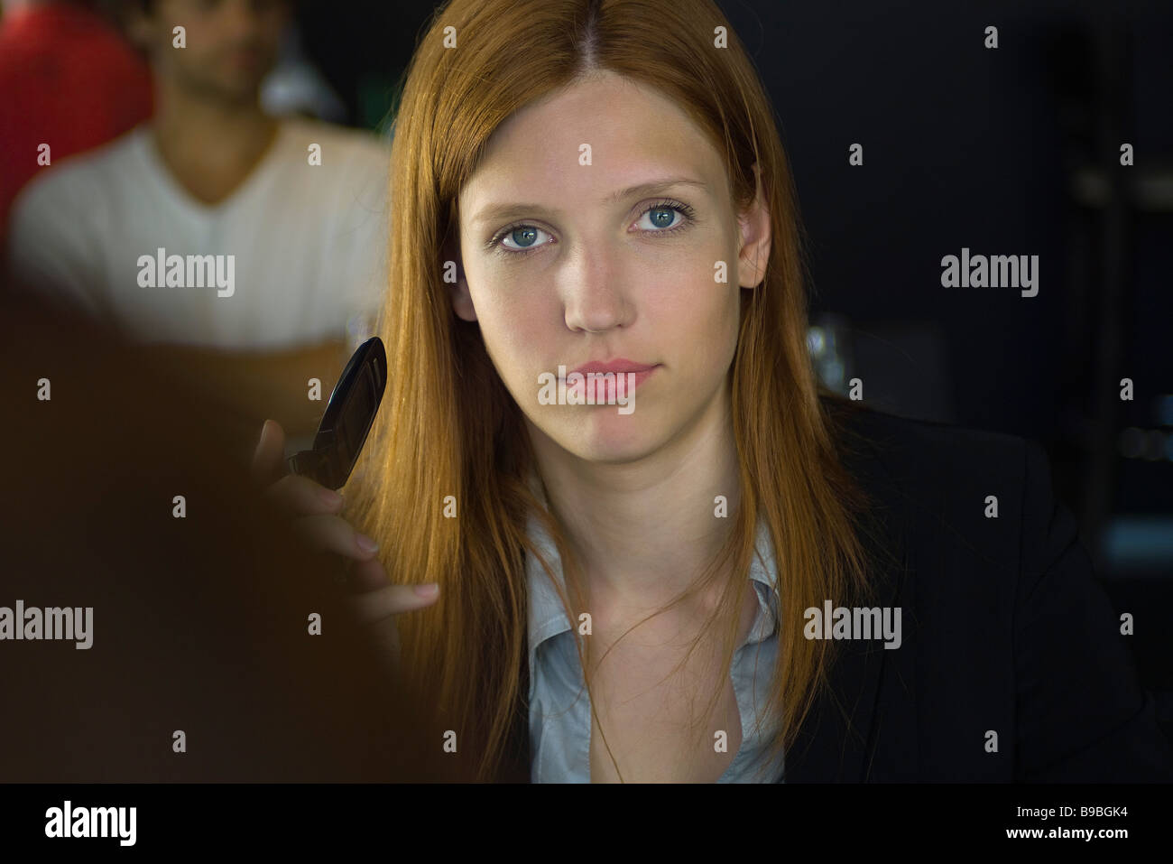 Woman holding cell phone, regardant at camera Banque D'Images