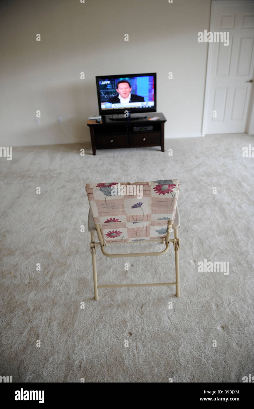 La télévision écran plat de assise seule dans un salon vide avec chaise pliante Banque D'Images