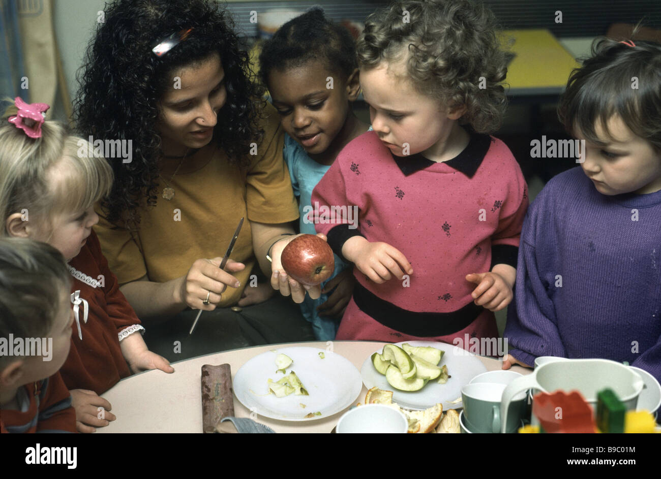 Maternelle de couper une pomme en nursery school girls watch Banque D'Images