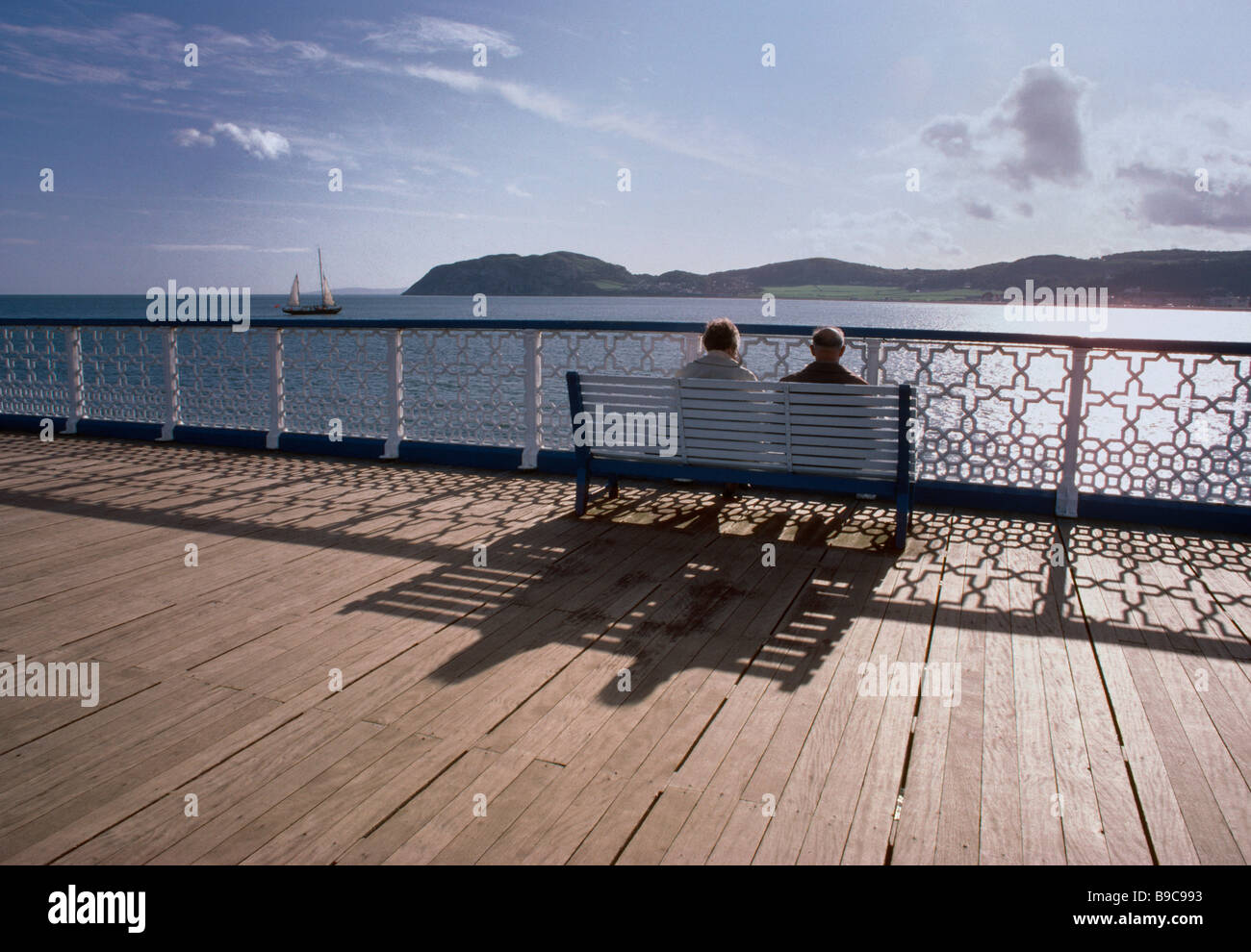 COUPLE DE RETRAITÉS DÉTENTE SUR UNE JETÉE À LLANDUDNO NORTH WALES UK EUROPE Banque D'Images