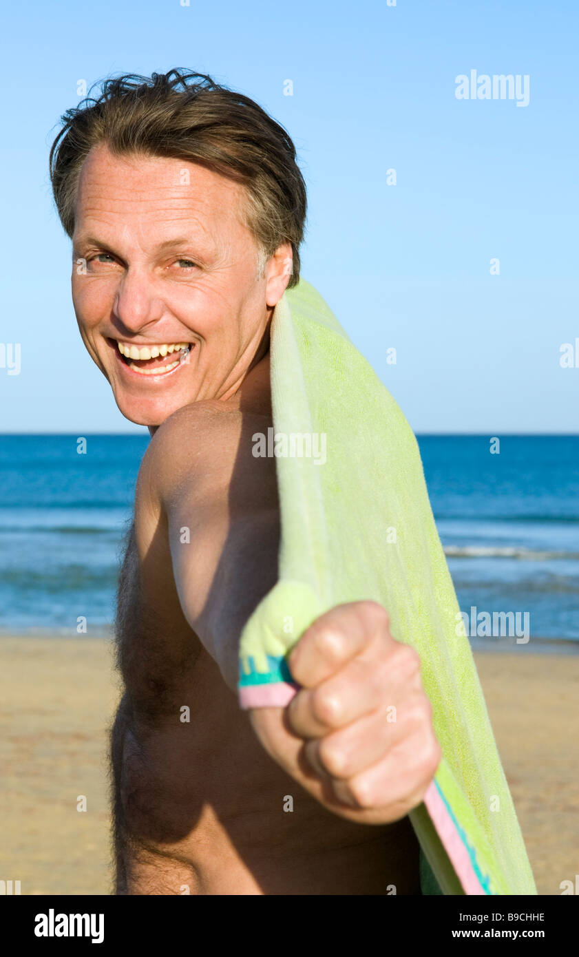 Une quarantaine de rire heureux homme d'avoir du plaisir avec sa serviette au cours d'une belle journée à la plage. Banque D'Images