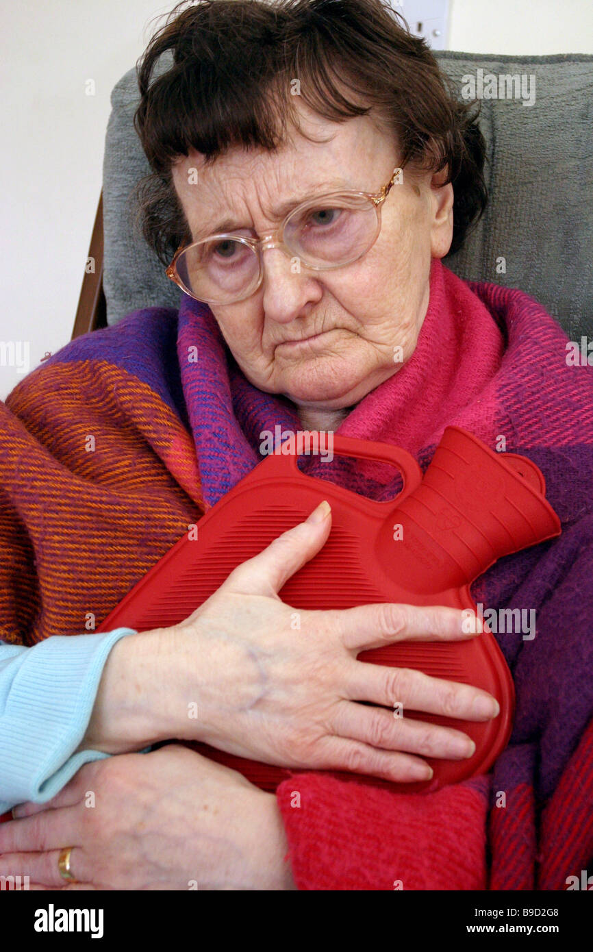 Femme plus âgée atteinte de démence hugging hot water bottle Banque D'Images