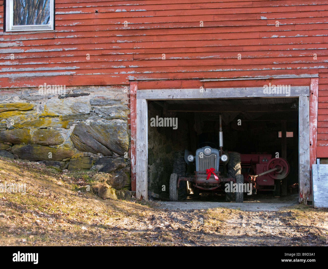 Tracteur agricole ancien avec ruban de Noël repose dans une grange du Vermont Banque D'Images