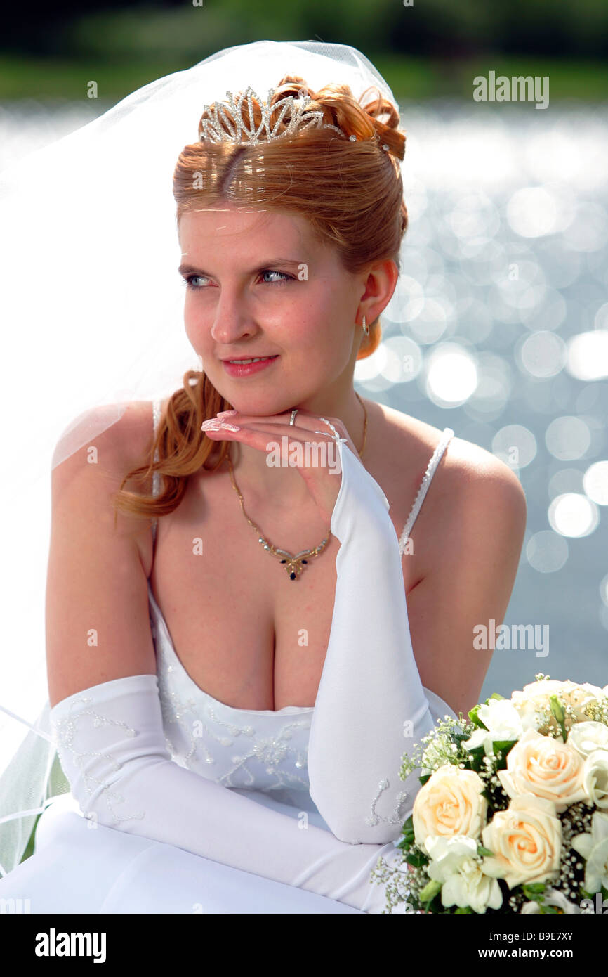 Moitié du corps, portrait of smiling bride avec voile et le bouquet était assis en face du lac Banque D'Images