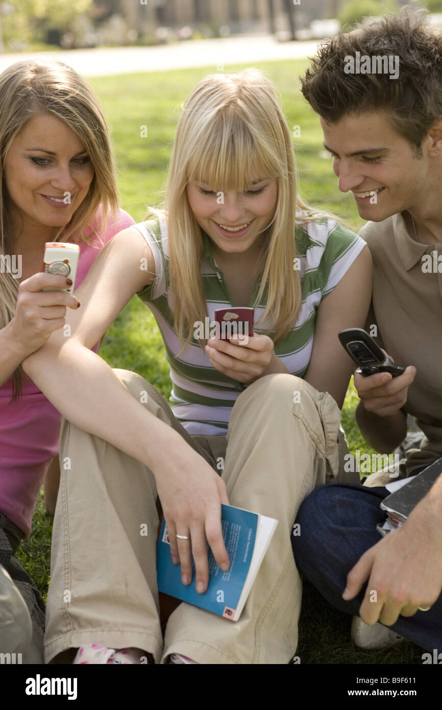 Les élèves de l'école pré-records SMS téléphone mobile s'asseoir allègrement les gens série lecture écriture élèves adolescents amis Banque D'Images