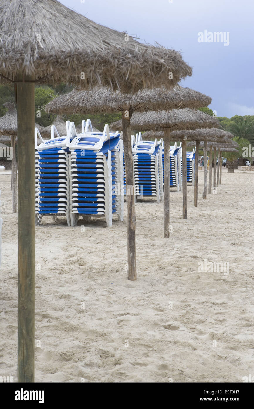 Hôtel-plage parasols transats empilés plage déserte de sable plage paille-parapluies parasols chaises longues chaise longue Banque D'Images