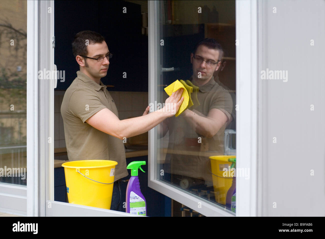 Jeune homme nettoyer les fenêtres Banque D'Images