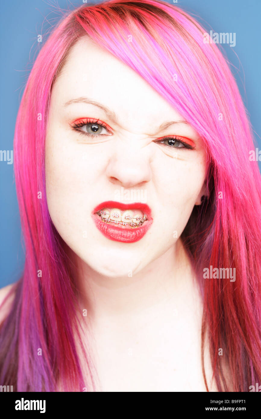 Jeune adolescente avec des cheveux roses portant des accolades grondant à huis clos. Banque D'Images