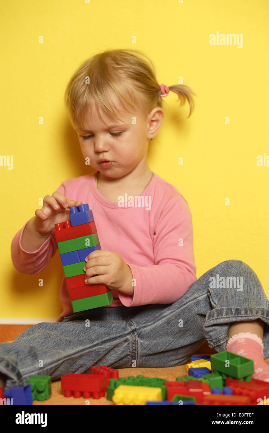 Les personnes composant la fille blonde tout-petits enfants jouer à jeu coloré coloré pierres compose ensemble-jouet est en phase de développement Banque D'Images