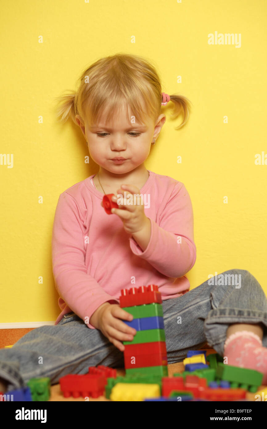 Les personnes composant la fille blonde tout-petits enfants jouer à jeu coloré coloré pierres compose ensemble-jouet est en phase de développement Banque D'Images