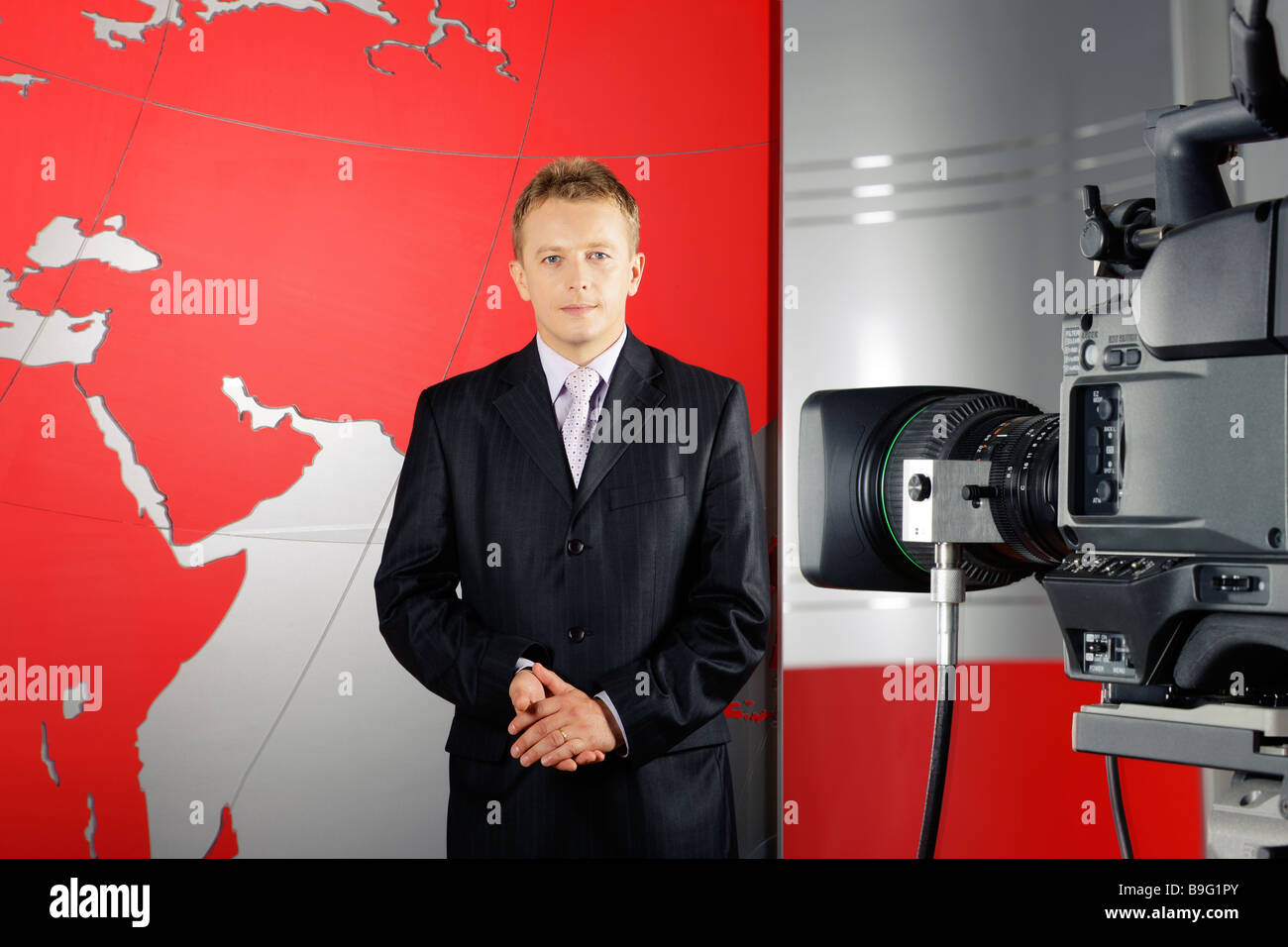 L'âge moyen sérieux journaliste d'attrayants debout devant la caméra vidéo dans un studio de télévision Banque D'Images