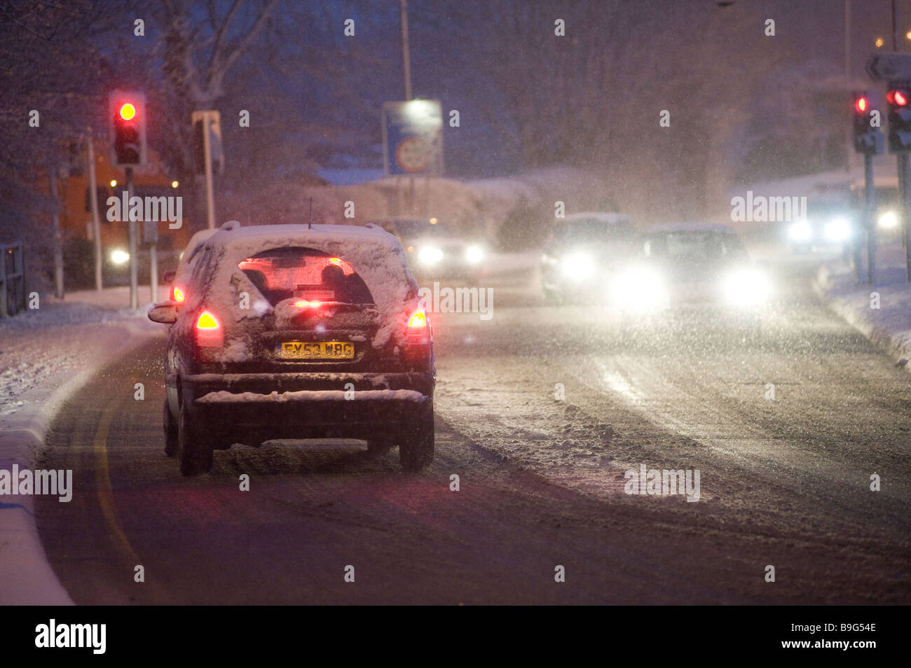 Voitures en attente à un feu rouge sur une route couverte de neige pendant la nuit pendant l'hiver en Angleterre Banque D'Images