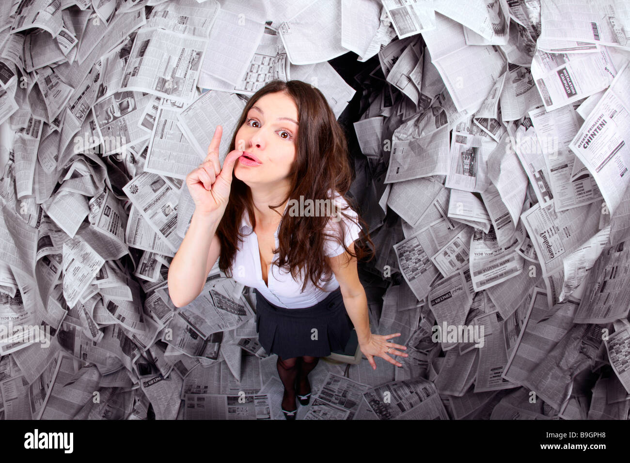 Femme d'affaires entouré par les journaux exprimant le signe peu en contraste avec tous les journaux autour du symbole de media Banque D'Images