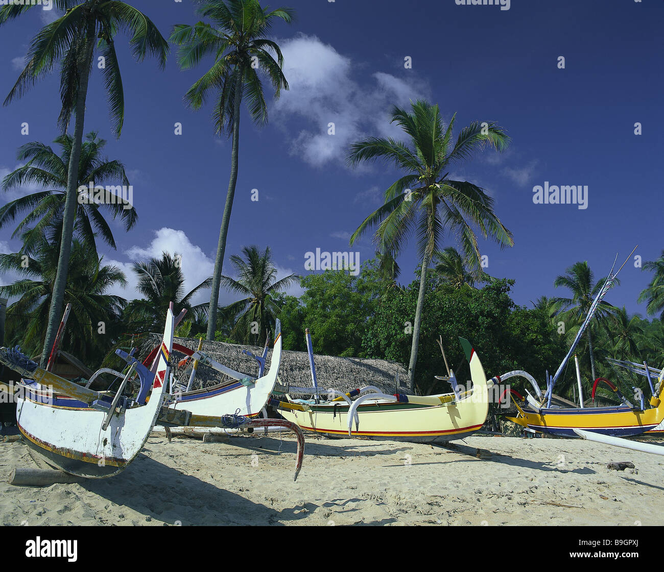 Île de l'Indonésie Bali Candi Dasa beach outrigger côte-côte bateaux pêche économie plage plage de palmiers bateaux à rames Banque D'Images