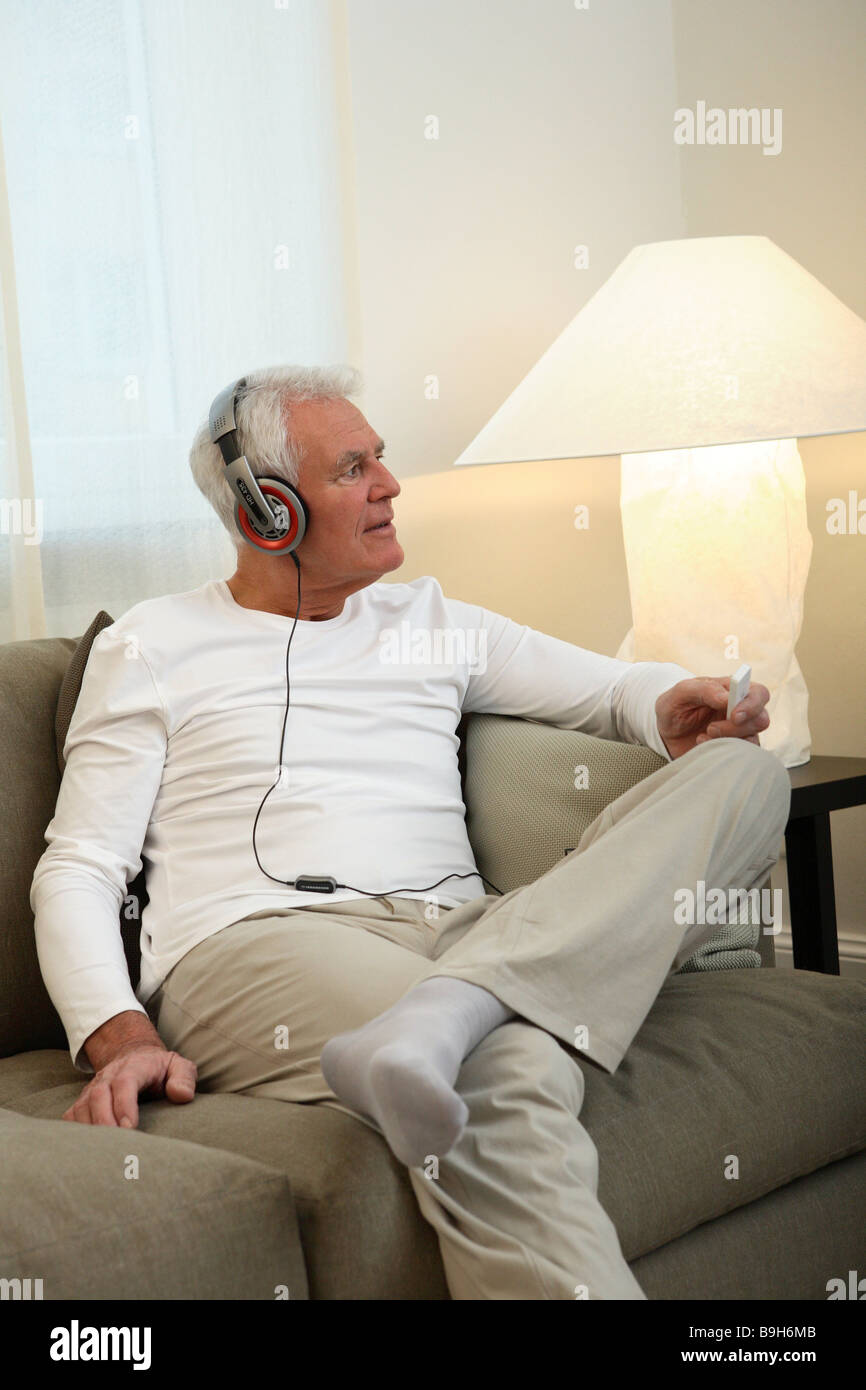 Salon canapé senior casque série assis relaxation personnes aînés retraités l'homme aux cheveux blancs la musique de relaxation-entend Banque D'Images